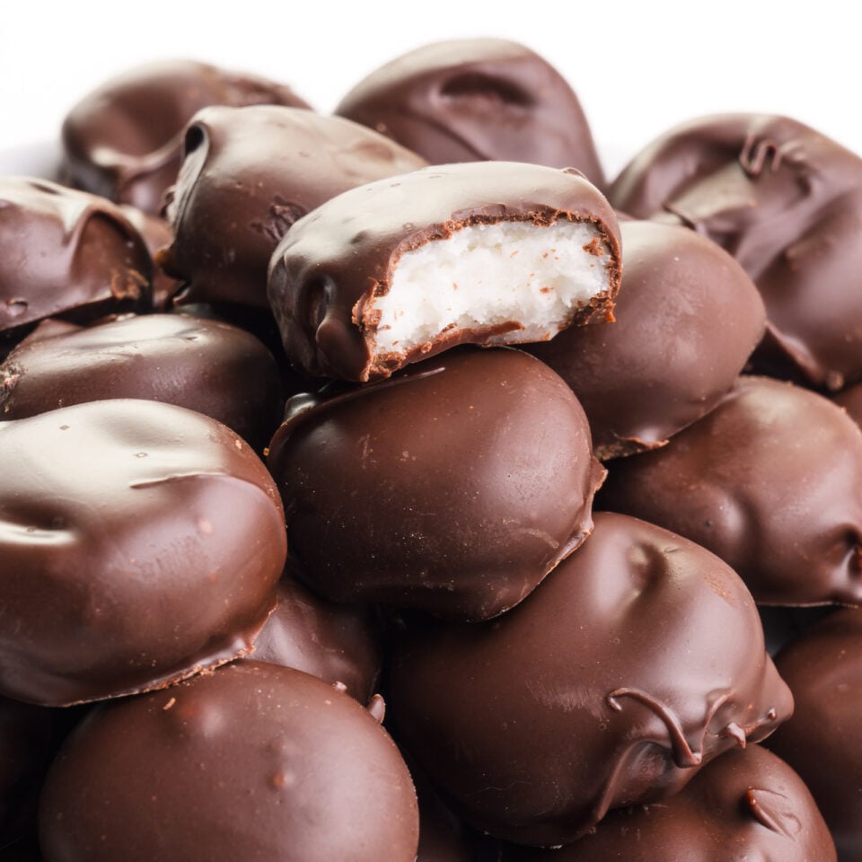 A vegan junior mint with a bite taken out sits on top several of the candies.