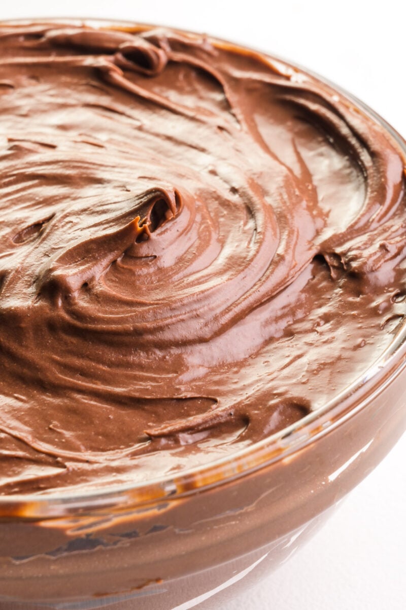 A bowl of whipped ganache frosting sits on a white table.