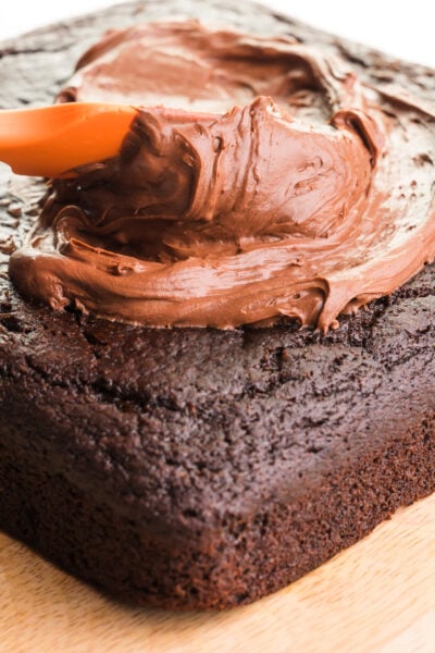 A cake is being topped with whipped ganache frosting.