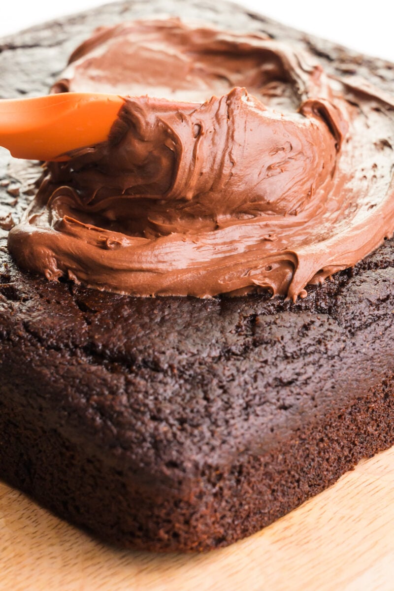 A cake is being topped with whipped ganache frosting.