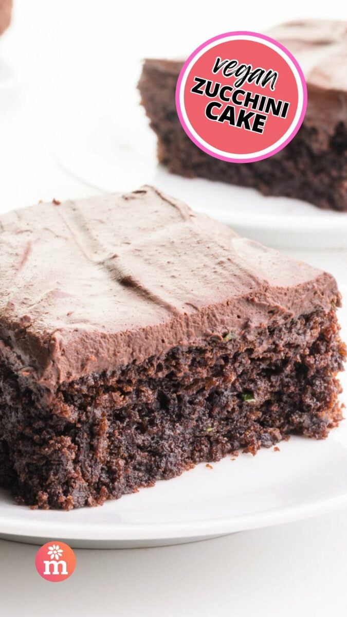 A slice of frosted chocolate cake sits on a plate. The text reads, Vegan Zucchini Cake.