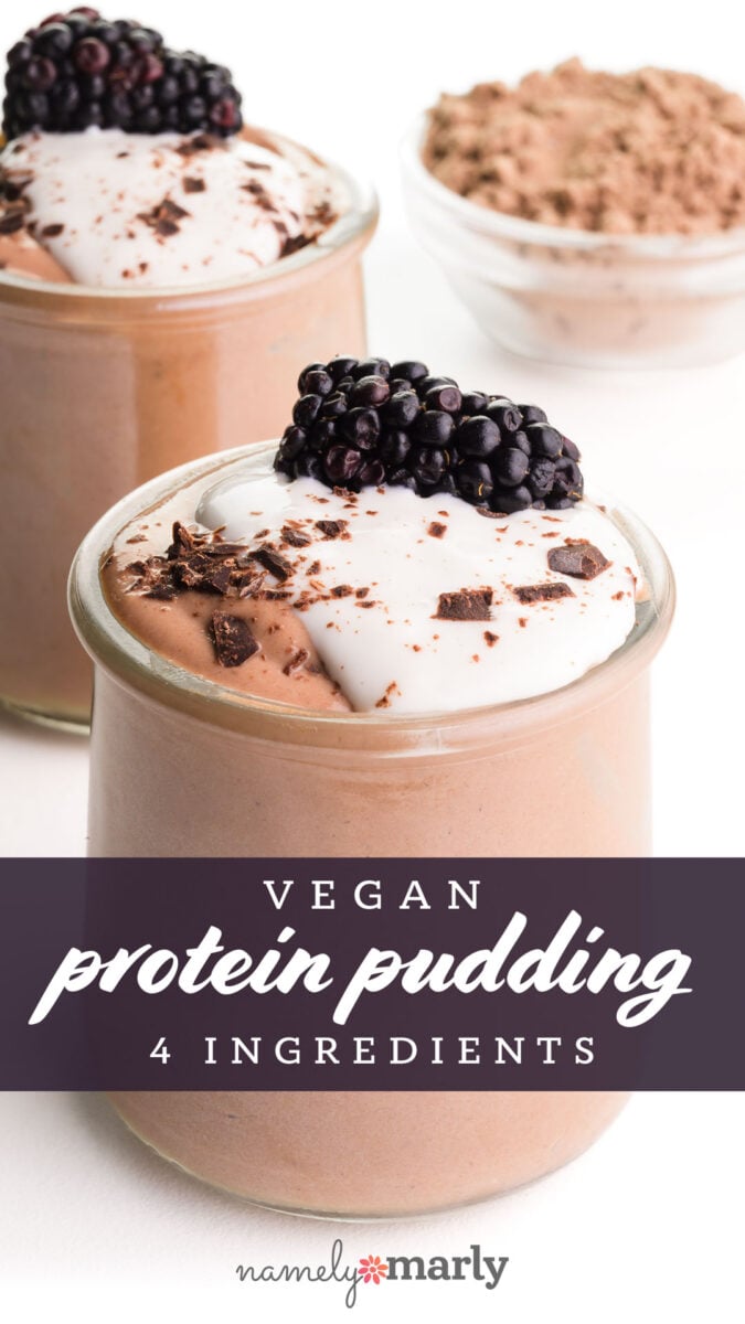 Vegan protein pudding topped with blackberries and chocolate shavings in glass jars, with a bowl of cocoa powder in the background.