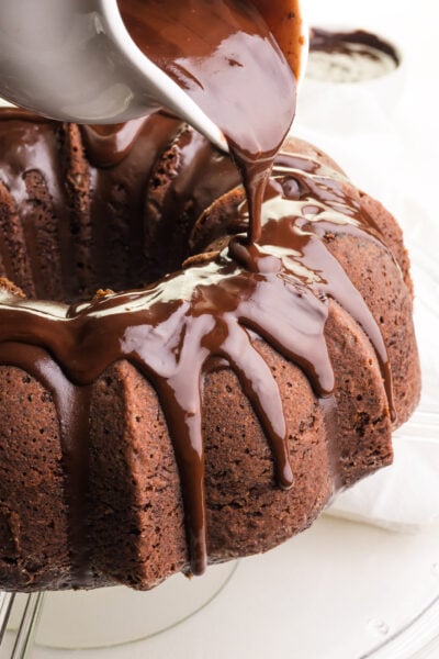Chocolate sauce is being poured over a chocolate Bundt Cake.