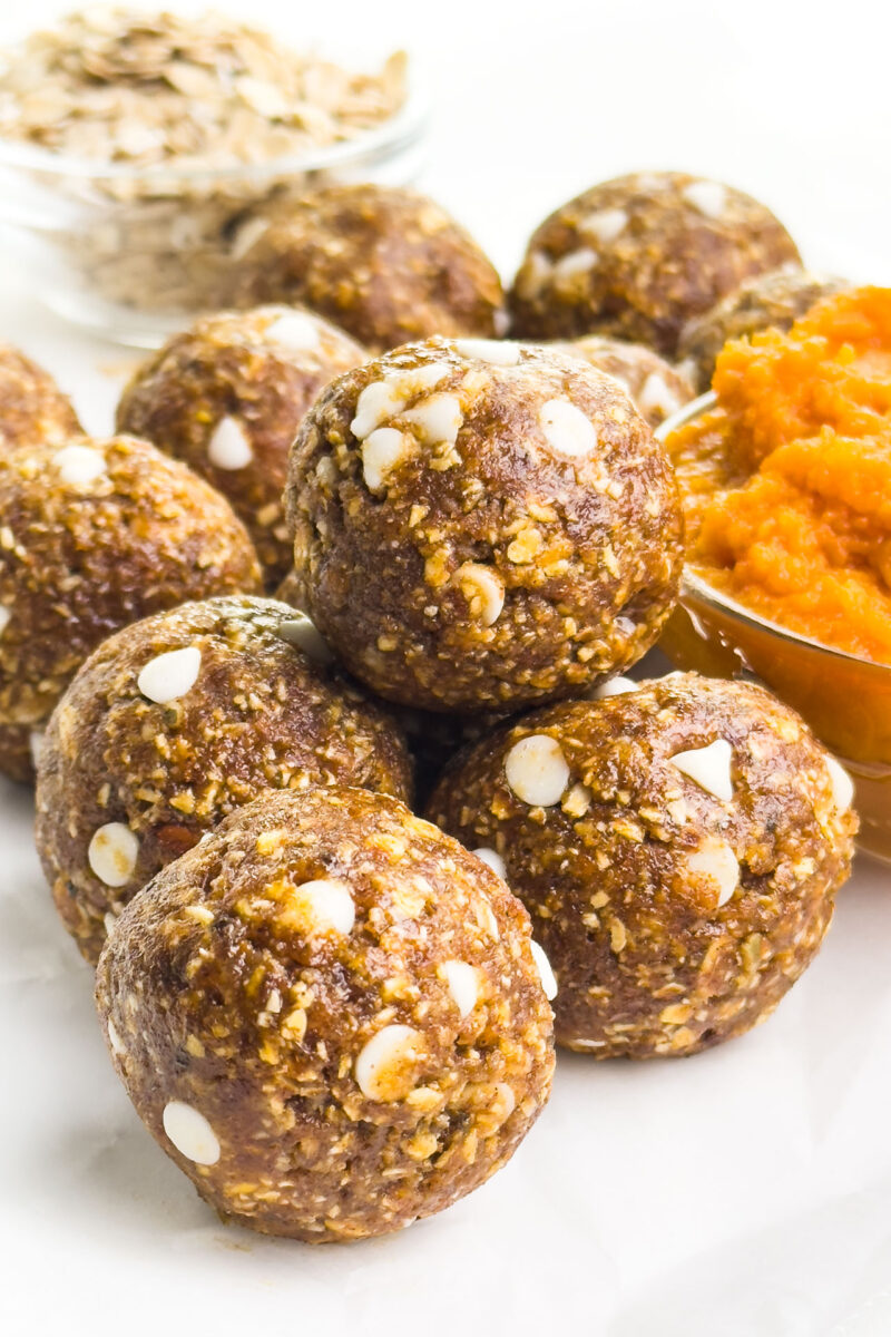 Pumpkin energy balls sit beside bowls of pumpkin puree and oats.