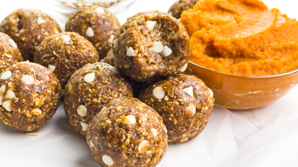A stack of pumpkin energy balls next to a bowl of pumpkin puree.