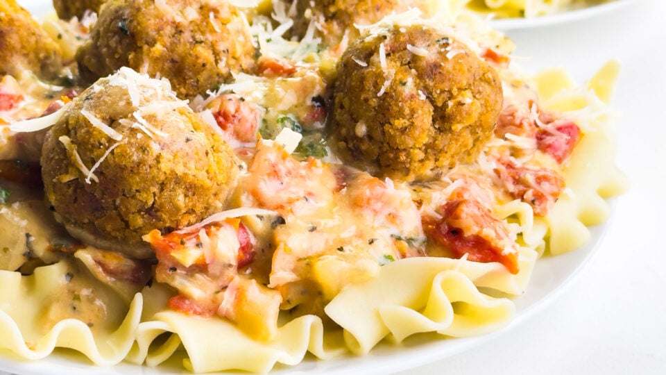A plate of meatballs on sauce over noodles.