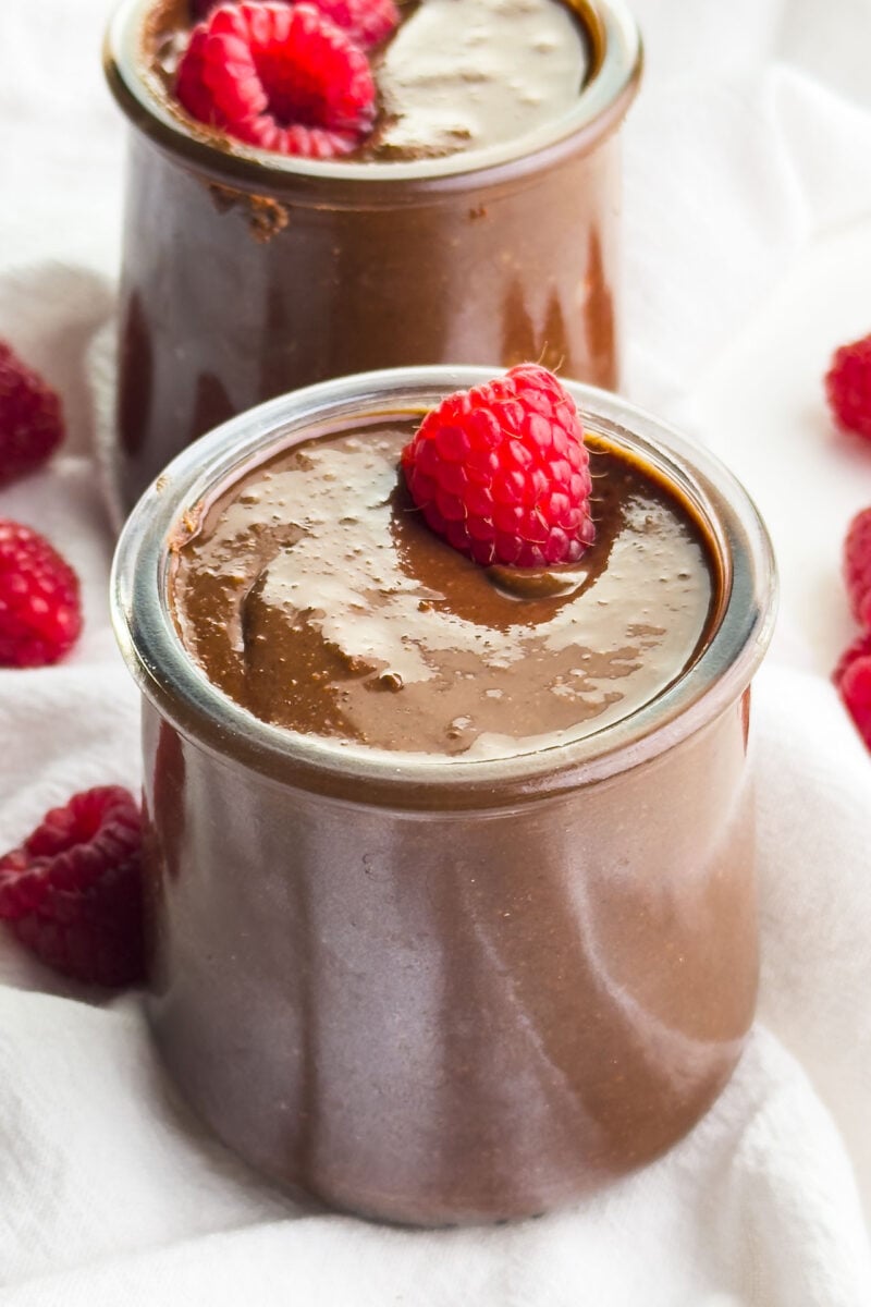 Two jars of vegan Nutella have fresh raspberries on top.