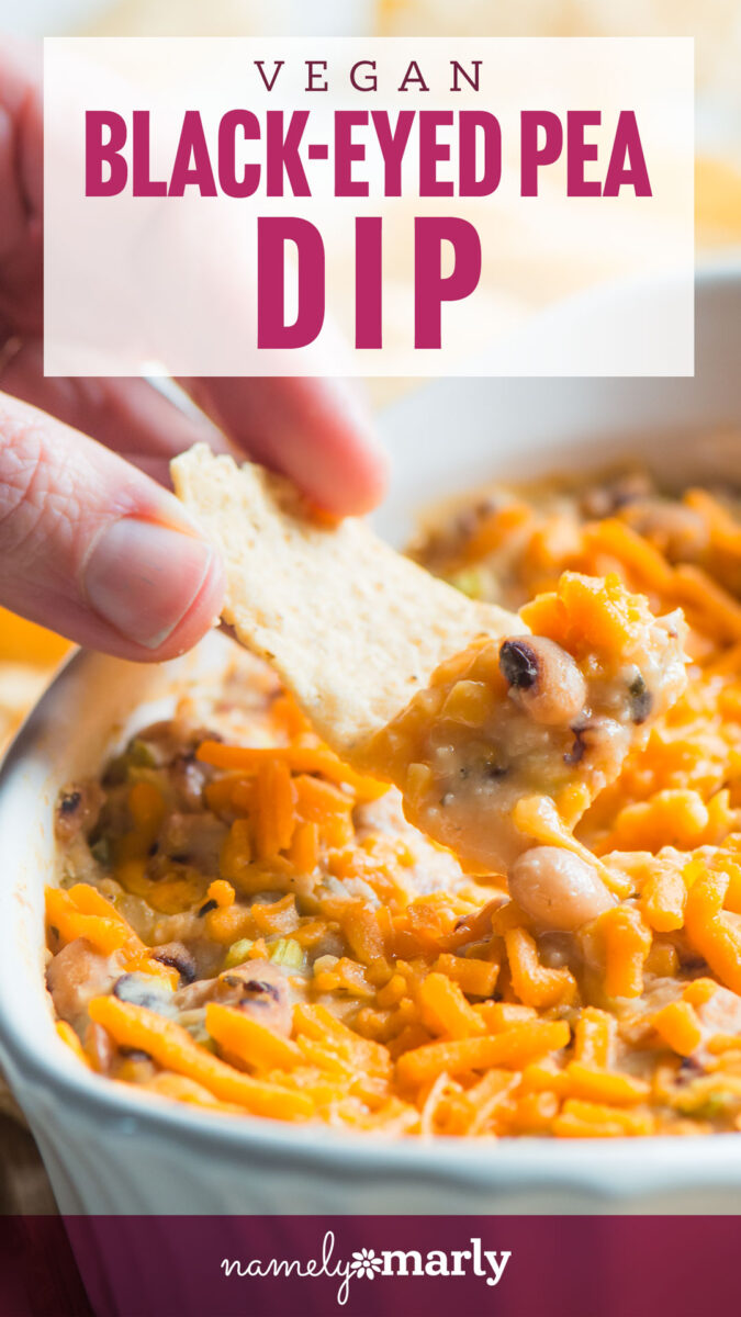 Vegan black-eyed pea dip topped with shredded cheese, served with a cracker being dipped into the dish.