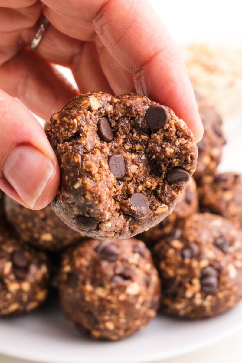 A hand holds a chocolate energy ball with a bite taken out.