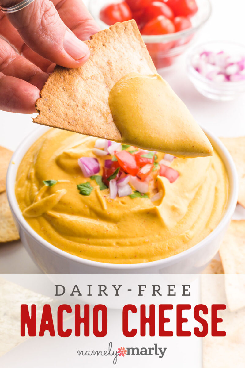 A hand holds a tortilla with cheese sauce hovering over a bowl of more sauce. The text reads, Dairy-Free Nacho Cheese.