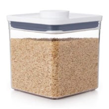 Clear container filled with brown rice, featuring a white lid and a rectangular shape.