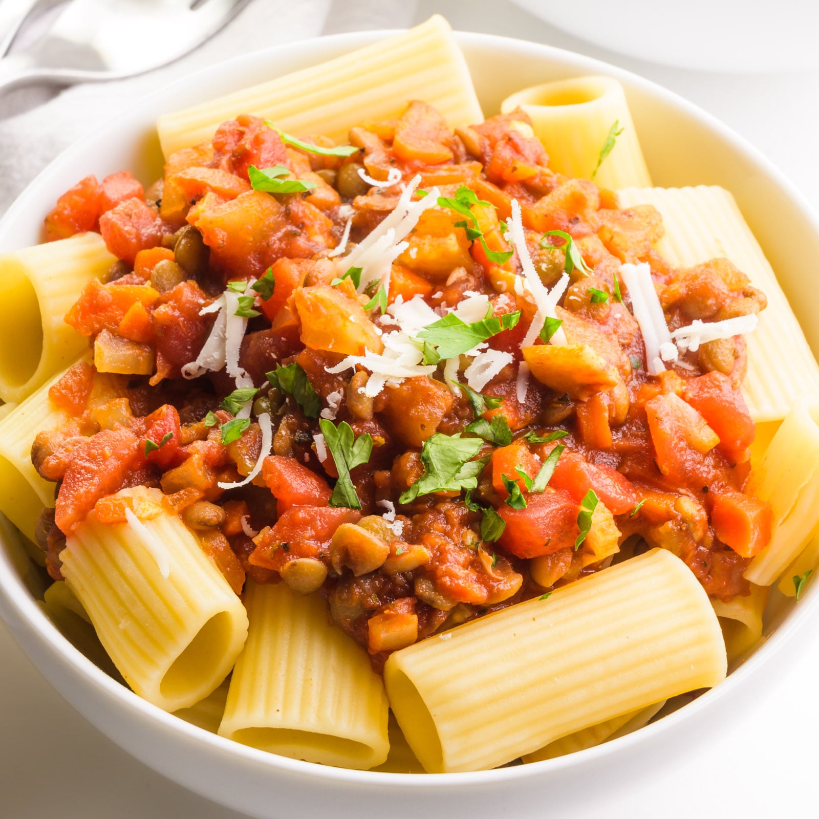 A bowl of lentil bolognese with grated parmesan on top.