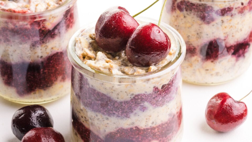 A closeup of cherry overnight oats with fresh cherries on top.