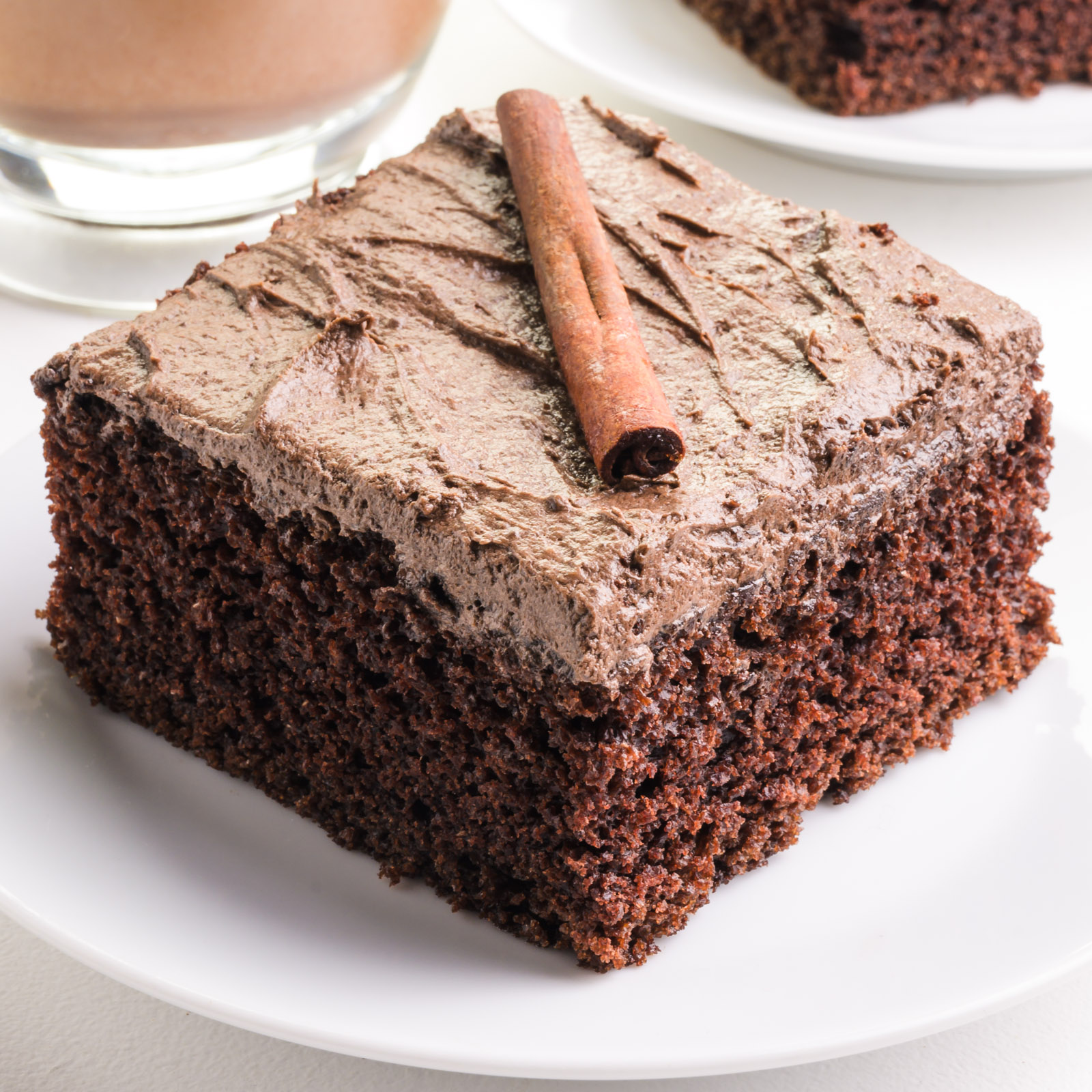 A slice of chocolate chai cake with a cinnamon stick on top.