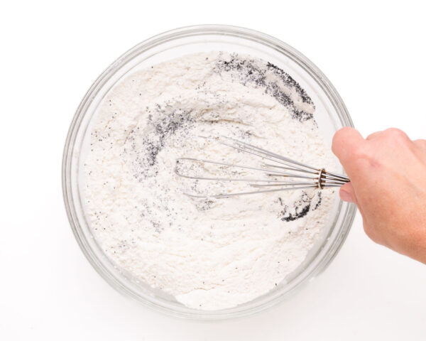 A flour mixture is being whisked int a mixing bowl.