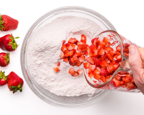 Fresh chopped strawberries are being poured into a flour mixture.