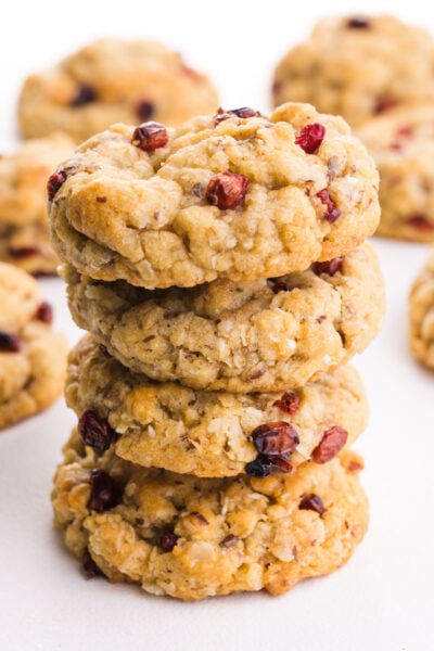 A stack of oatmeal cookies made with rice krispies and dried fruit sit on a white table.