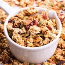 A bowl of granola sits in a pan with more granola.