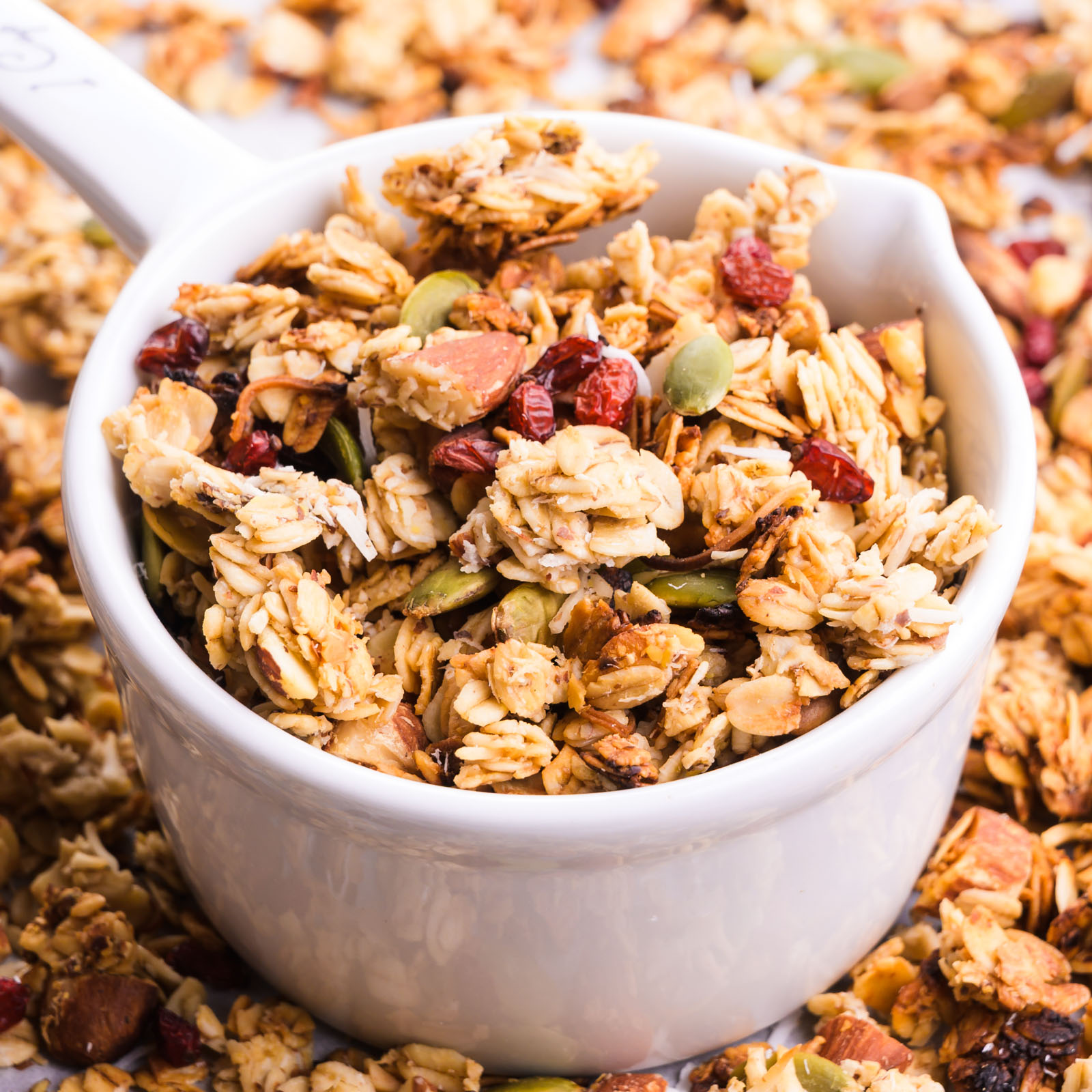 A bowl of granola sits in a pan with more granola.