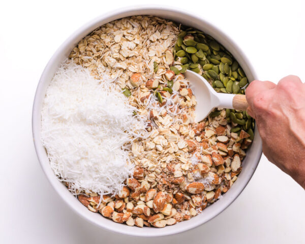 Granola ingredients are being stirred together in a bowl.