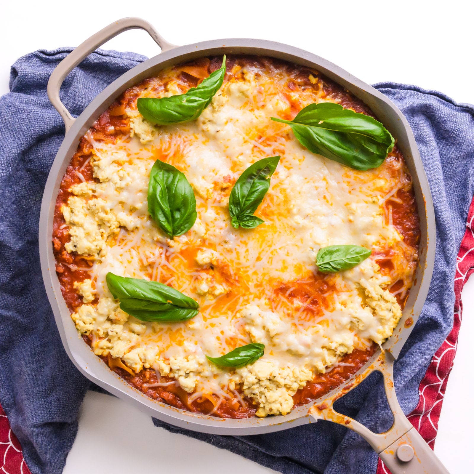 Looking down on skillet full of skillet lasagan with melted cheese and herbs on top.