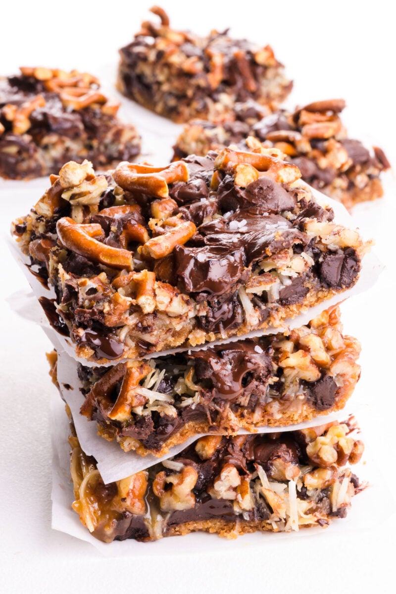 A stack of magic bars are on a white table with more of the treats behind it.
