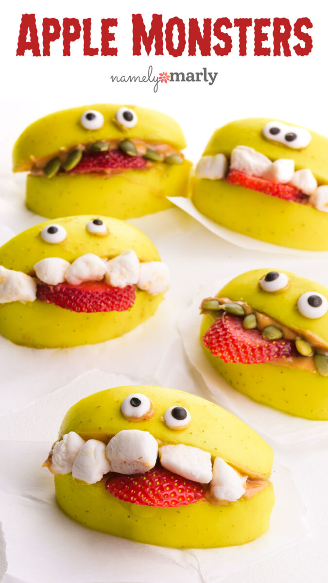 Bright yellow apple halves decorated as playful monsters with eyes, strawberry tongues, and various toppings.