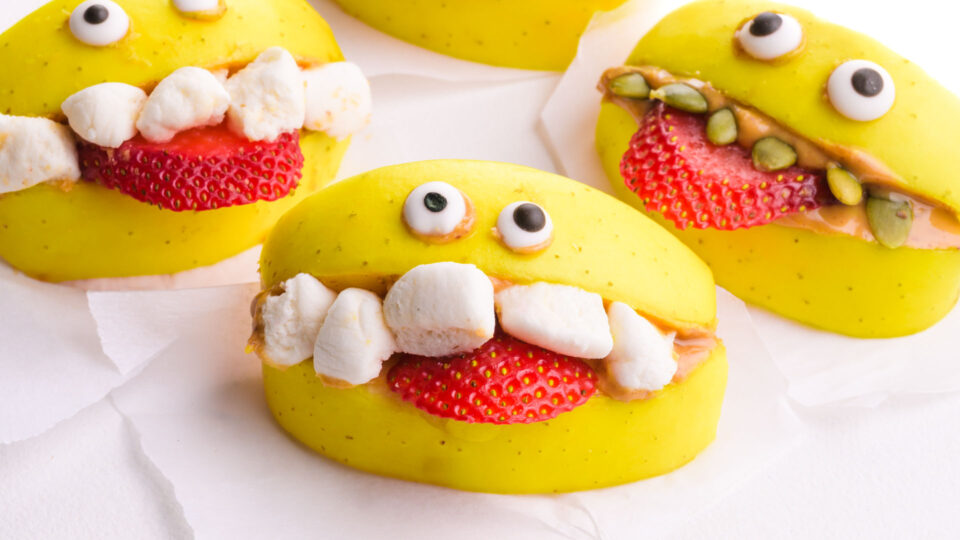 Three apple treats are decorated with marshmallows and candy eyes to look like monster bites.