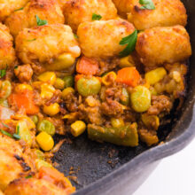 Vegan shepherd's pie is topped with tater tots in a cast iron skillet.