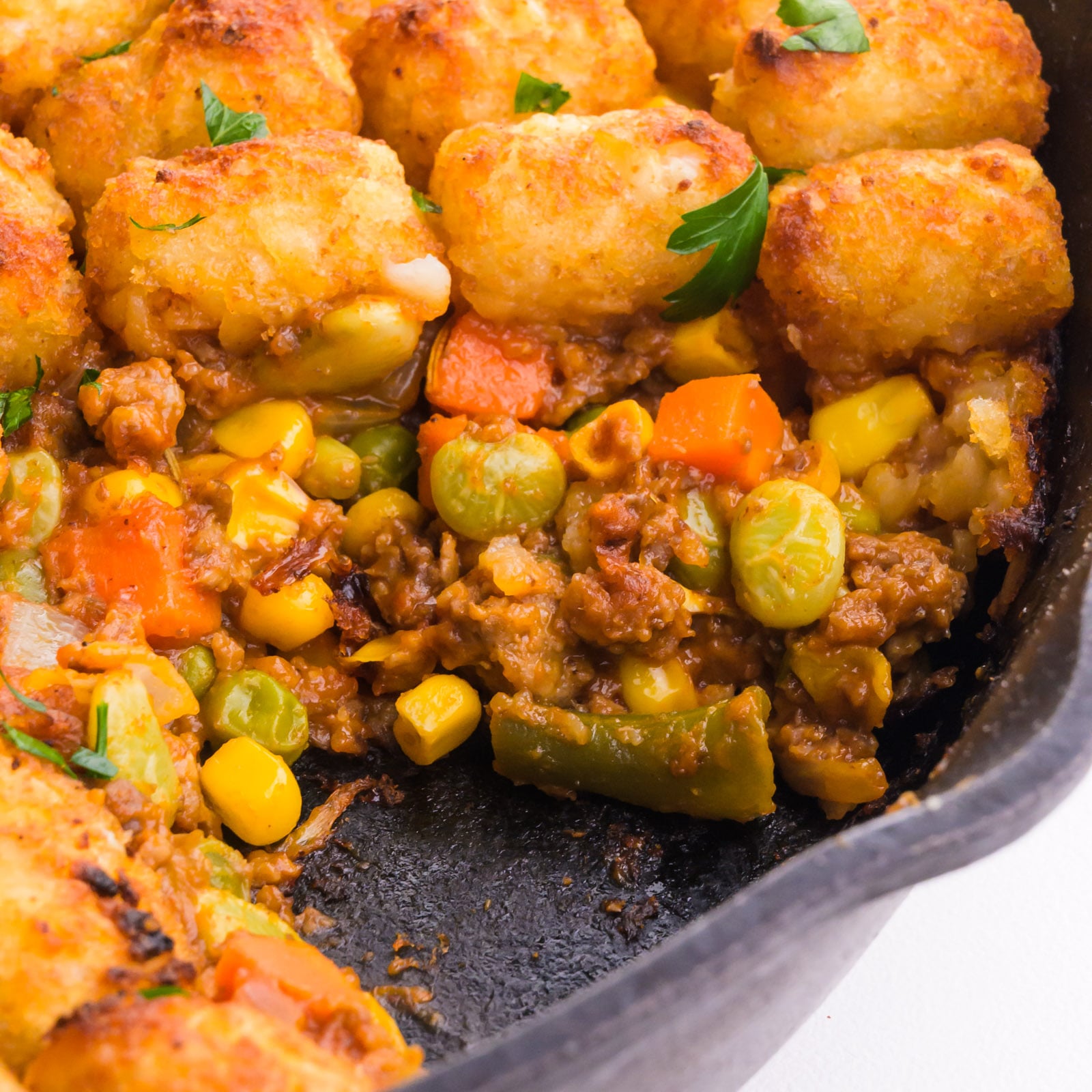 Vegan shepherd's pie is topped with tater tots in a cast iron skillet.