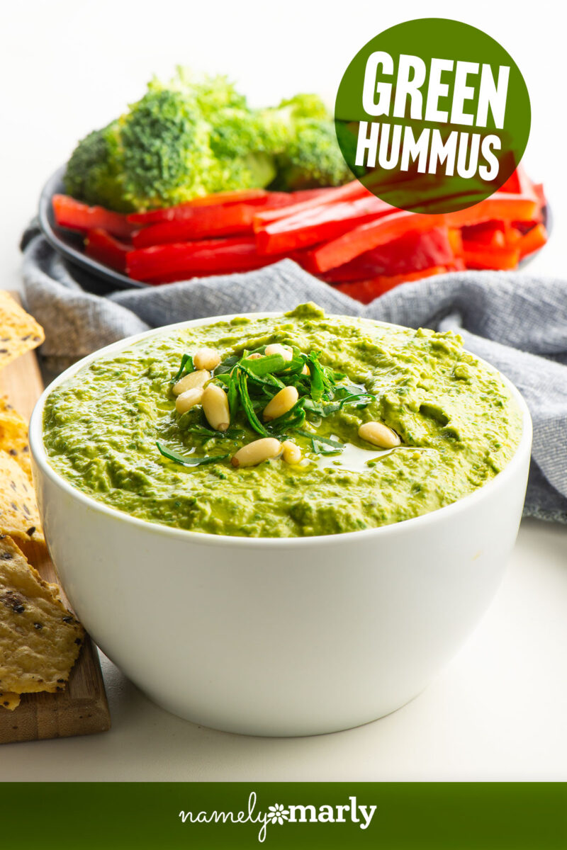 a bowl of green hummus topped with pine nuts and text that reads green monster hummus