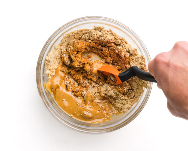 A spoon stirs together a peanut butter mixture in a bowl.