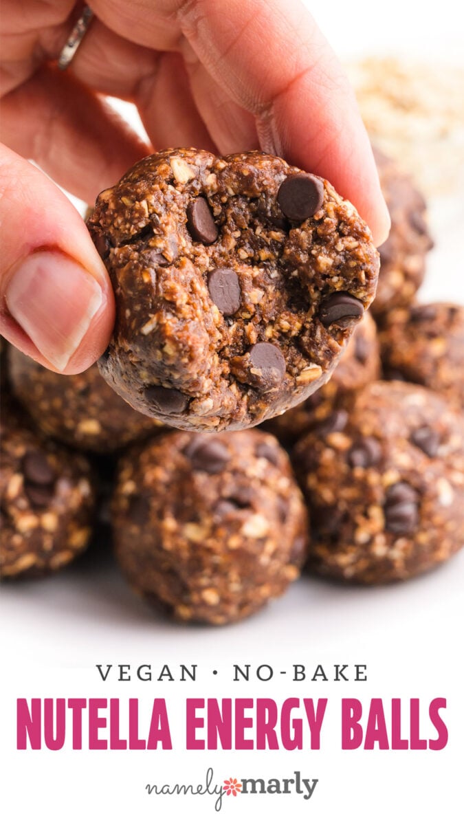 Hand holding a half of a chocolate chip Nutella energy ball, with more energy balls in the background.