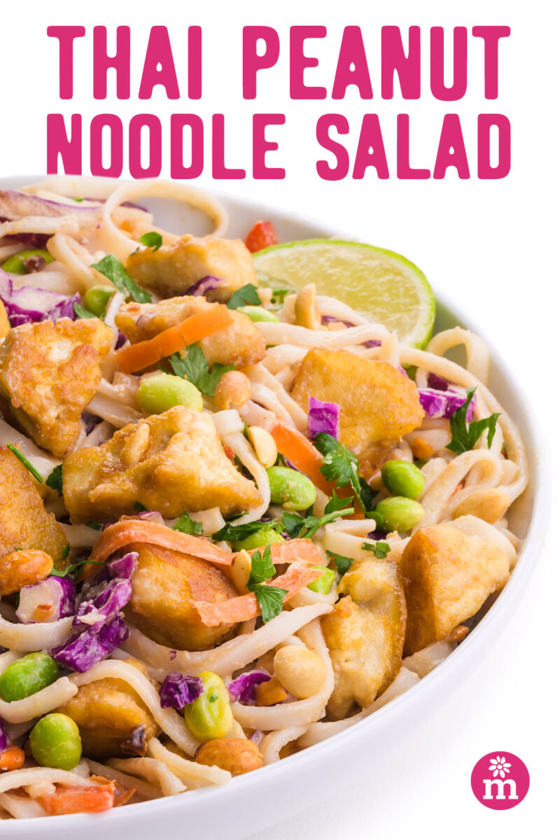 Colorful Thai peanut noodle salad with crisp vegetables and garnished with lime.