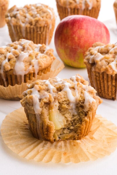 Several apple crumble muffins sit near an apple.