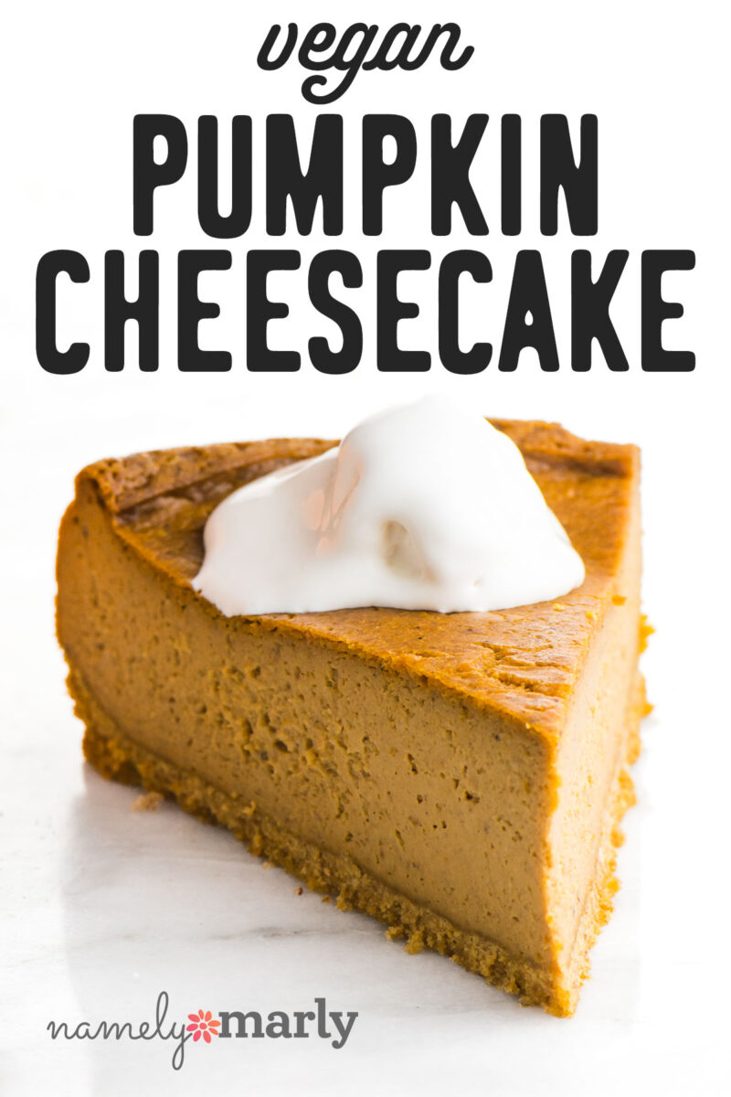 Vegan pumpkin cheesecake slice topped with a dollop of cream on a marble surface.