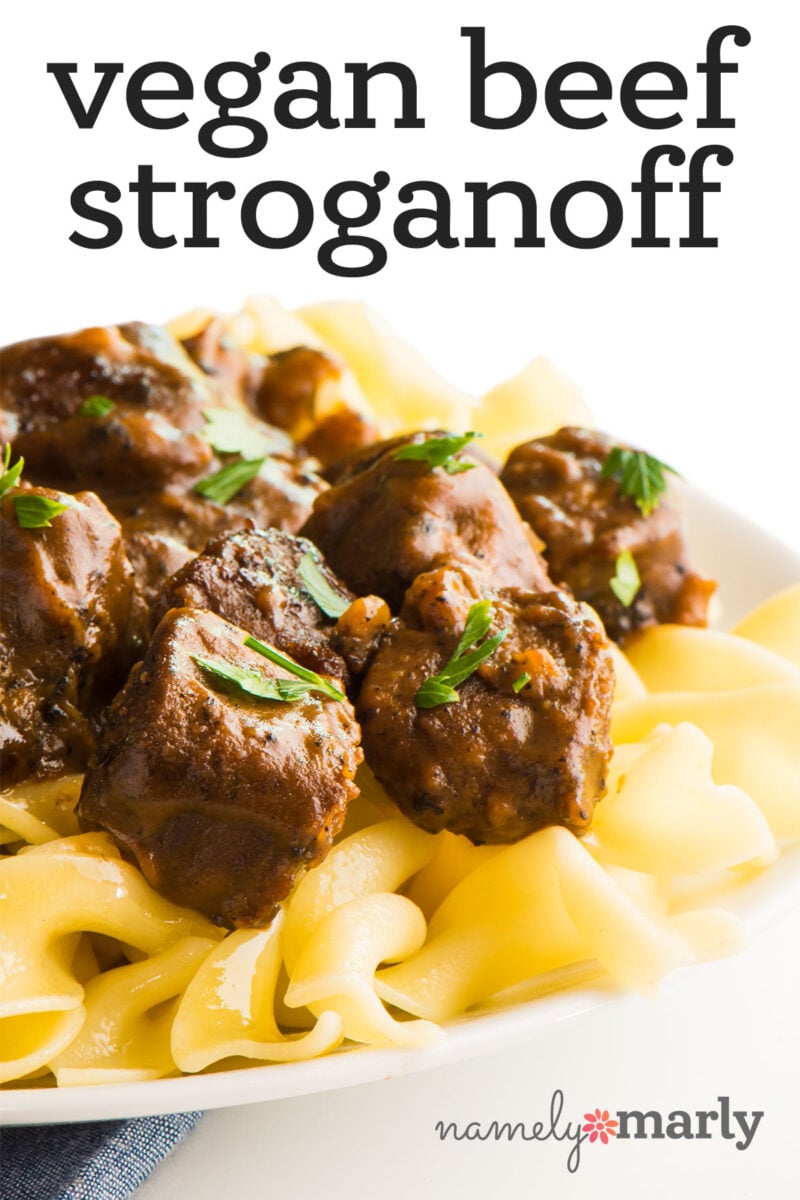 Vegan beef stroganoff served over egg noodles, garnished with fresh parsley.