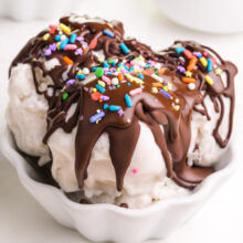 A bowl of ice cream has chocolate magic shell topping and sprinkles.