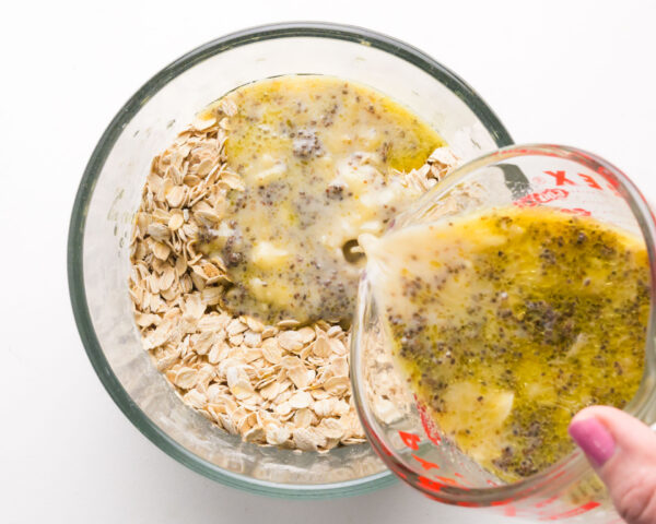 Wet ingredients are being poured into a bowl with dry ingredients.