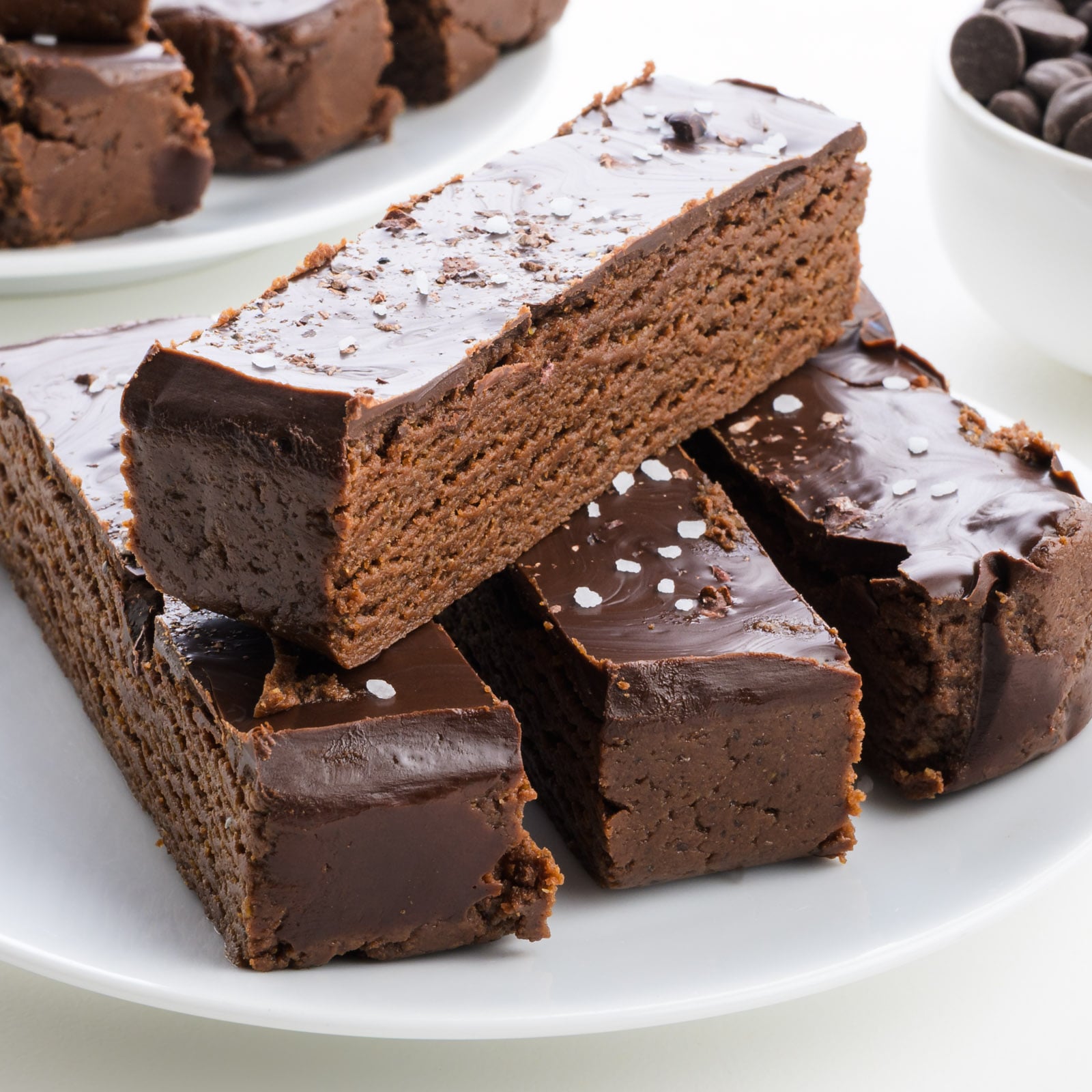 Chocolate Brownie Protein Bars topped with glossy chocolate and a sprinkle of sea salt, served on a white plate.