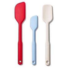 Three silicone spatulas in red, blue, and cream colors with ergonomic handles.